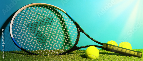 Tennis racket and balls on green grass against light blue background, space for text. Banner design © New Africa