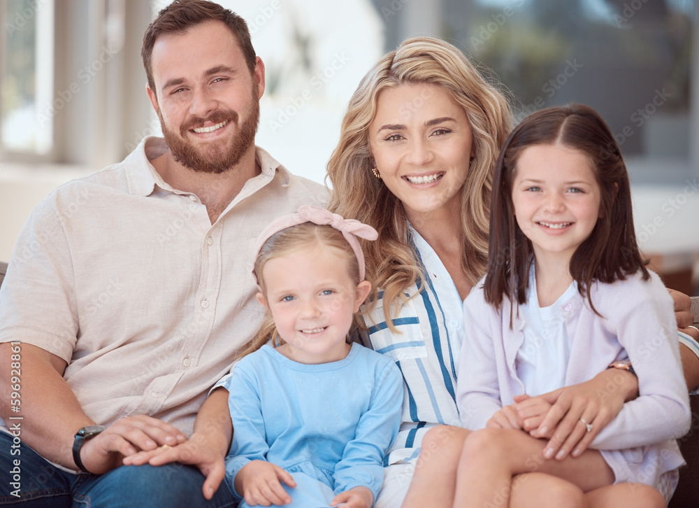 Portrait of a smiling young caucasian family sitting close together on the sofa at home. Happy adorable girls hugging and bonding with their mother and father on a weekend. Happy couple and daughters Portrait of a smiling young caucasian family sitting close together on the sofa at home. Happy adorable girls hugging and bonding with their mother and father on a weekend. Happy couple and daughters