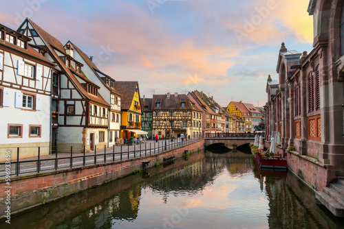 Picturesque half timber buildings across from the riverfront Marché Couvert covered market at sunset along the Lauch River in the Petite Venice area of Colmar, France.