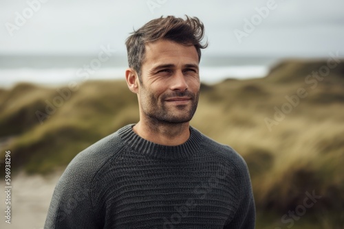 Portrait of handsome man standing on beach, looking at camera.