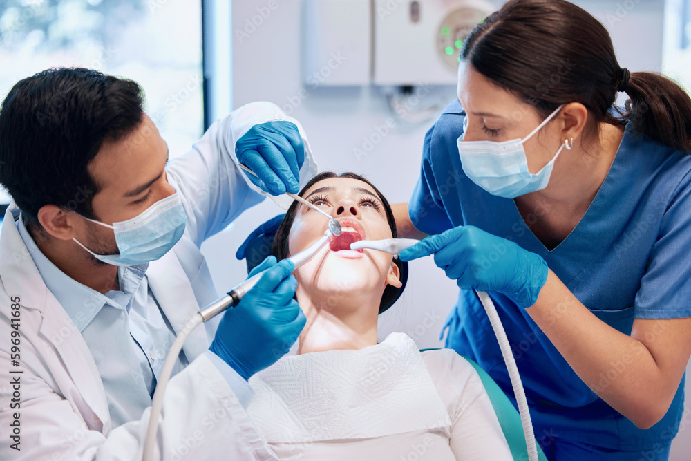 Theyre hard at work. Shot of a young dentist working on a patients teeth with his assistant. Theyre hard at work. Shot of a young dentist working on a patients teeth with his assistant.