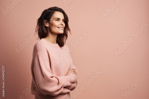 Portrait of a smiling young woman standing with arms crossed isolated over pink background