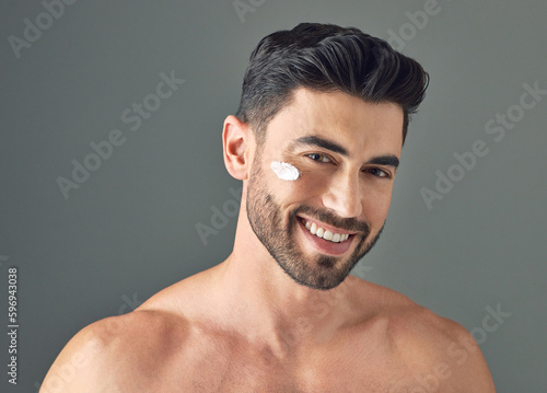 I keep my moisture barrier in good shape. Studio shot of a handsome young man posing with moisturiser on his face.