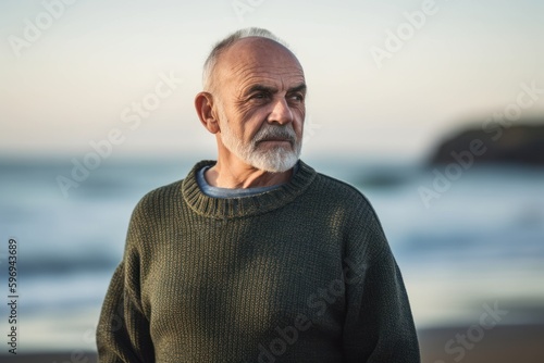 Portrait of senior man standing on beach at the day time. Looking at camera