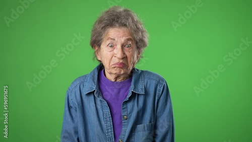 Portrait of happy elderly senior old woman with wrinkled skin and grey hair shrugging shoulders and gesturing I do not know isolated on green screen background. photo