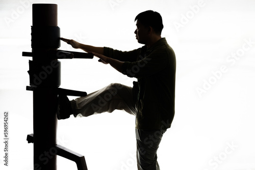 Silhouette of a fighter Wing Chun and wooden dummy on a white background. Wing Chun Kung Fu Self defense.