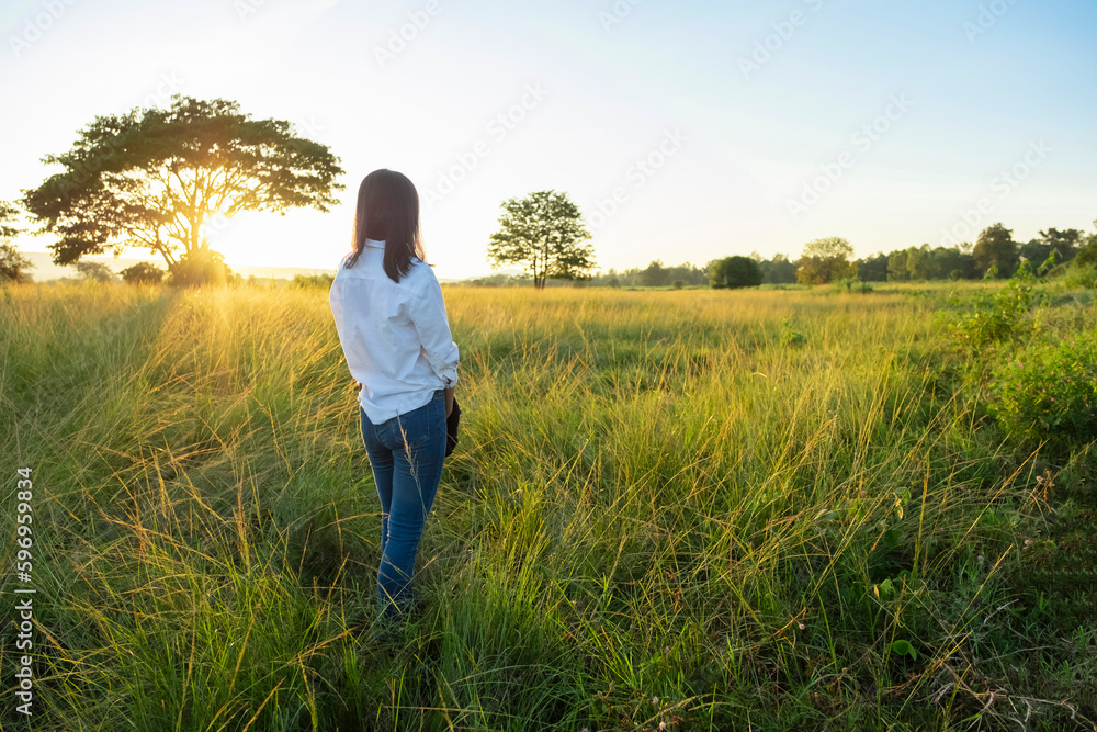 An Asian traveler is standing and relaxing with beautiful dramatic landscape in the morning sunrise. 