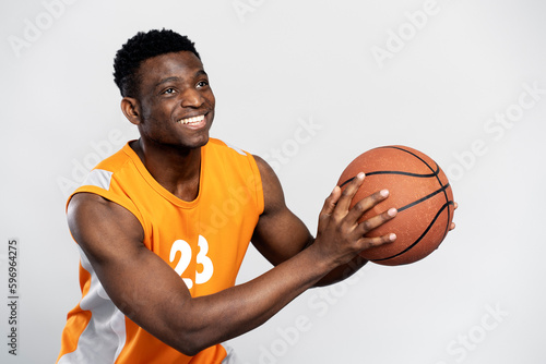 Portrait of confident smiling African American man playing basketball, catching ball isolated on white background. Sport competition concept 