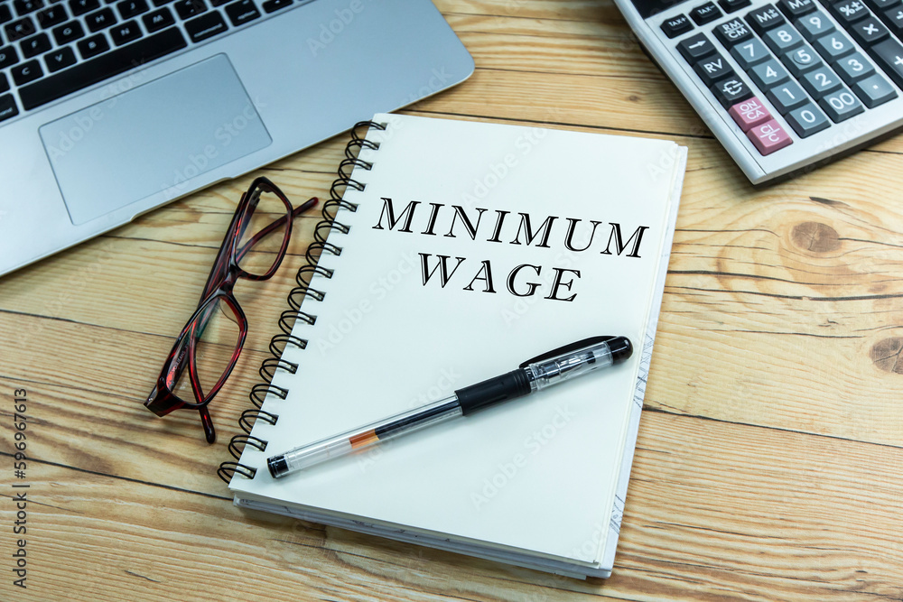 Minimum wage text on notepad with calculator and laptop. Minimum wage text on notepad with calculator and laptop.