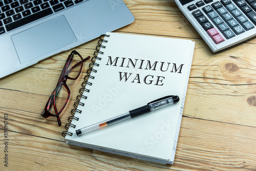 Minimum wage text on notepad with calculator and laptop.