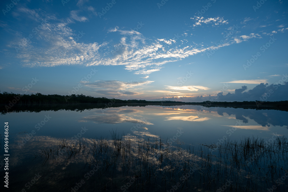 Colorful sunrise cloudscape reflected in calm water of Nine Mile Pond in Everglades National Park, Florida.