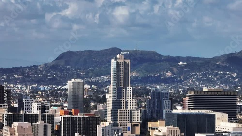 Zoomed shot of high rise office towers in city and Hollywood Sign in hills above city in distance. Los Angeles, California, USA