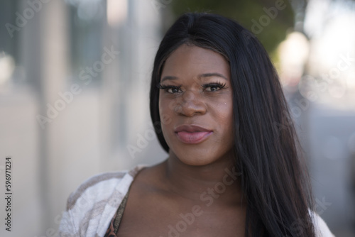 
With a cardigan-dress ensemble, a woman exudes a gentle, inviting smile, showcasing her true self as a Black transwoman and embracing the vibrant city life she now calls her own.