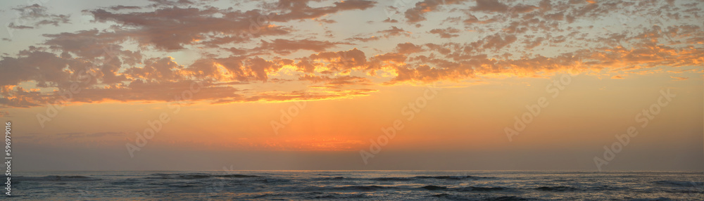 Panoramic view of beach sunset reflecting on the waves