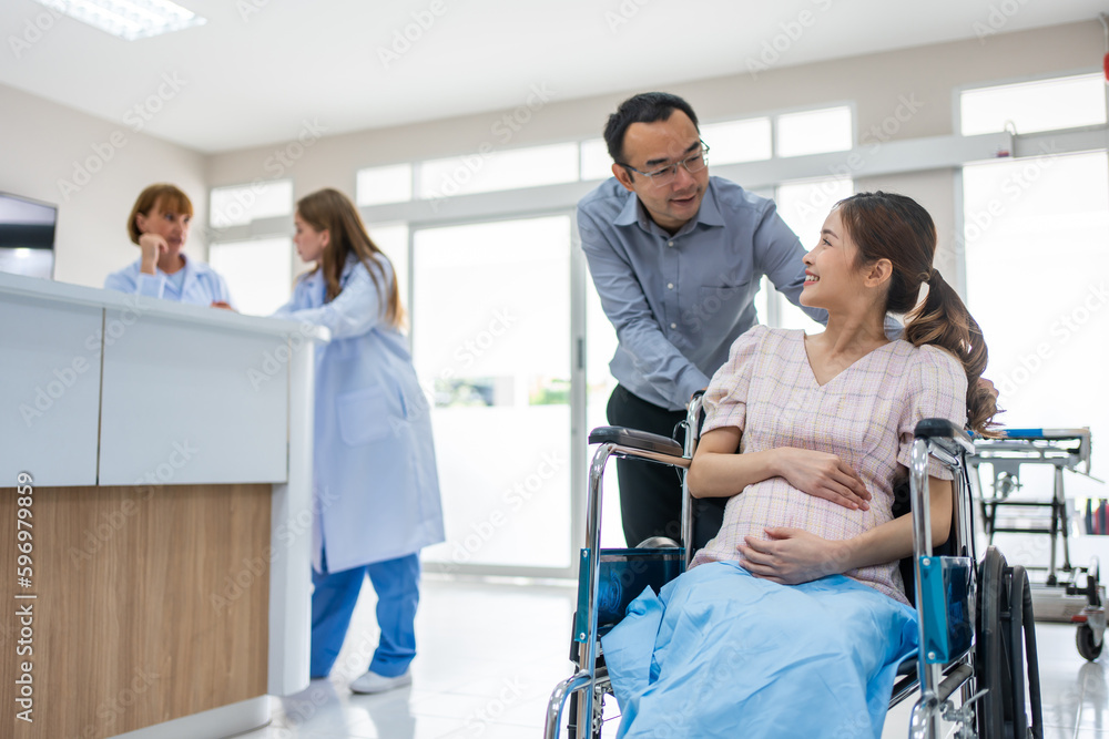 Asian husband taking care of pregnant woman sitting on wheelchair. Asian husband taking care of pregnant woman sitting on wheelchair.