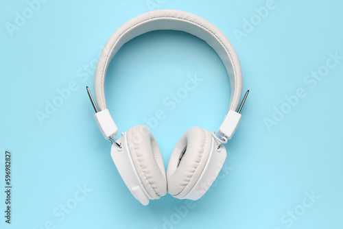 Modern white headphones on blue background