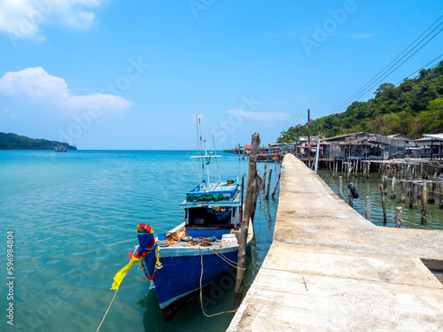 Ao Yai village, Koh kood, trat, Thailand. Scene of wooden boat near the bridge and fisherman village in the blue sea and green mountain with beautiful view with open sky on summer sunshine day.