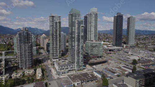 Aerial pan away from skyscrapers with mountains in the background near Vancouver, BC on a bright summers day photo