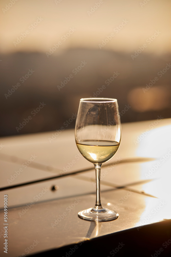a glass of champagne on the table against the background of the sunset. a glass of sparkling champagne stands on a table in a restaurant at sunset in summer