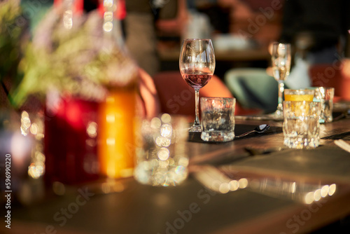 a restaurant. festively served table in a restaurant, glasses and a bottle of wine. Served table in a restaurant. Plates glasses cutlery on a long table, soft focus