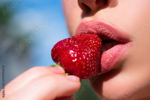 Strawberry in sensual lips. Red strawberry in woman sexy mouths close up.