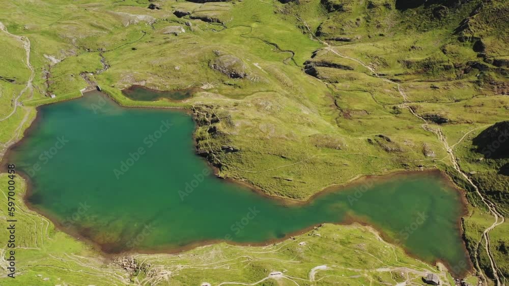 Aerial view : interesting shape of an alpine turquoise azure mountain lake beside bachalpsee among green meadows formed by melting snow in the swiss alp mountain trails of grindelwald at summer months Aerial view : interesting shape of an alpine turquoise azure mountain lake beside bachalpsee among green meadows formed by melting snow in the swiss alp mountain trails of grindelwald at summer months