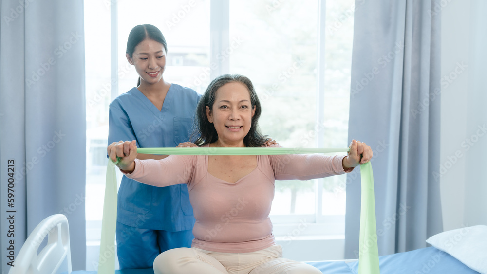 Fototapeta premium Asian Chinese female physiotherapist caregiver helping elderly woman exercise for recovery, prevention of osteoarthritis and osteoporosis.