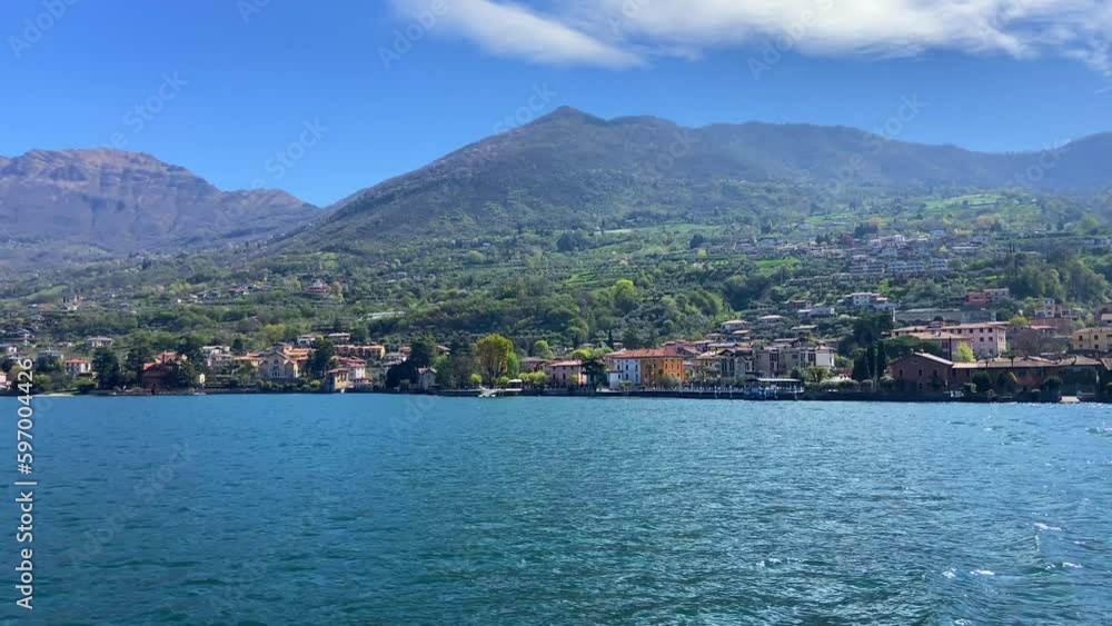 Sailing in lake Iseo with traditional Italian village in background Sailing in lake Iseo with traditional Italian village in background