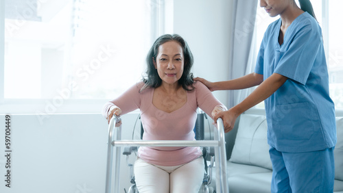 Asian Chinese female physiotherapist caregiver helping elderly woman exercise for recovery  prevention of osteoarthritis and osteoporosis.