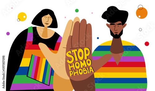 The LGBTQ couple, woman and  african american man in rainbow t shirt. They hold hands with lettering STOP HOMOPHOBIA .They celebrations international PRIDE DAY, LGBT parade.