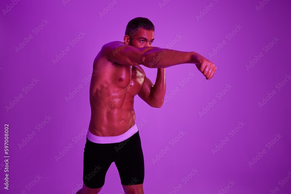 Man athletic body bodybuilder in briefs with nude torso abs full-length in the background fitness classes, purple colored light. Advertising, sports, active lifestyle, competition, challenge concept. 