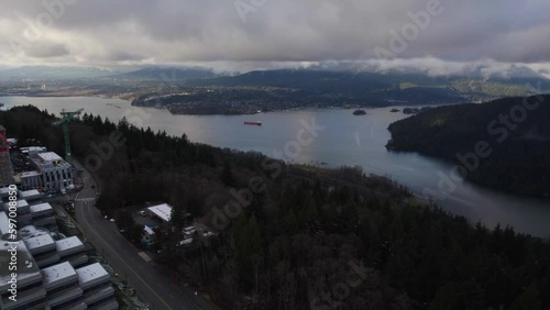 Ocean bay next to mountains with cities along the shore in Vancouver BC on a cloudy sunset