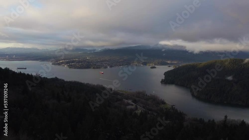 Ocean bay next to mountains with cities along the shore in Vancouver BC on a cloudy sunset