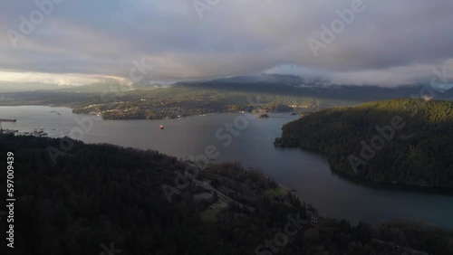 Ocean bay next to mountains with cities along the shore in Vancouver BC on a cloudy sunset