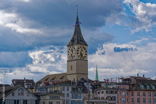 Clock tower of protestant church St. Peter with rooftops of the old town at City of Zürich on a blue cloudy spring day. Photo taken April 17th, 2023, Zurich, Switzerland.