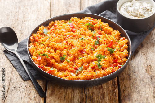Turkish pilaf from bulgur with vegetables and spices close-up in a bowl on a wooden table. Horizontal