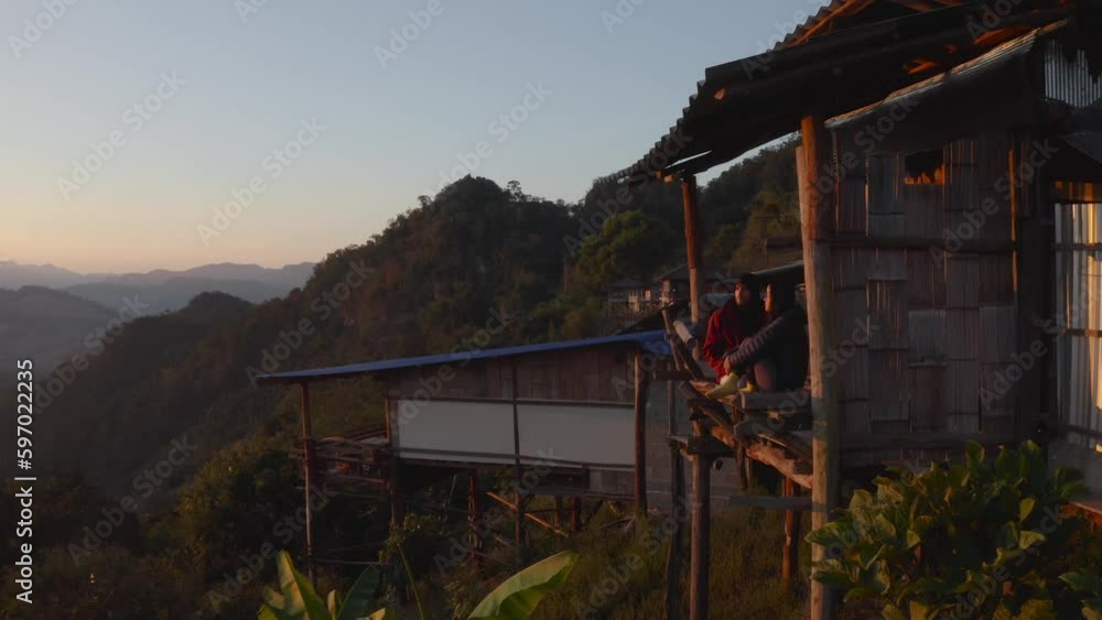 International couple enjoying sunset from wooden romantic cabin hotel in Southeast Asia. Aerial International couple enjoying sunset from wooden romantic cabin hotel in Southeast Asia. Aerial