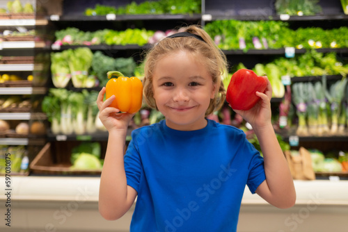 Kid with vegetables and peppers at grocery store. Portrait of child in a food store or a supermarket. Little kid going shopping. Healthy food for kids.