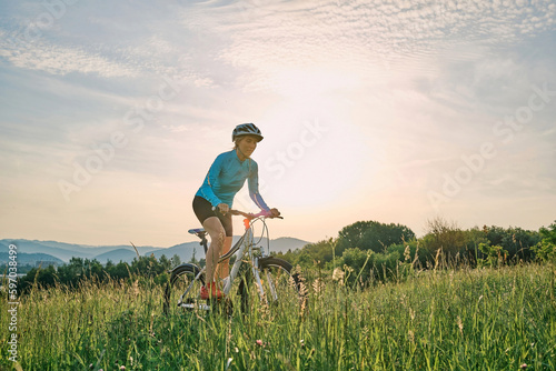 Cyclist Woman riding bike in helmets go in sports outdoors on sunny day a mountain in the forest. Silhouette female at sunset. Health care, authenticity, sense of balance and calmness. 