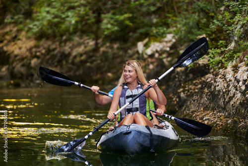 A young couple enjoying an idyllic kayak ride in the middle of a beautiful river surrounded by forest greenery