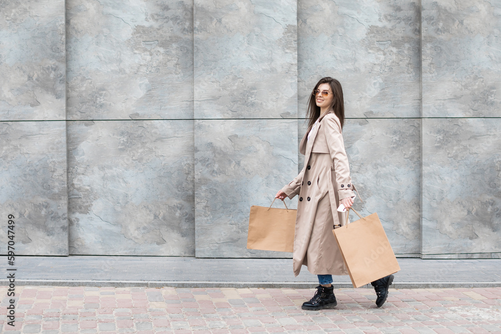 A girl in a casual clothes with shopping bags and lots of purchases near the shopping center smiling hands you her package, consumerism sale and people concept A girl in a casual clothes with shopping bags and lots of purchases near the shopping center smiling hands you her package, consumerism sale and people concept