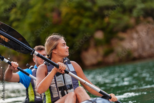 A young couple enjoying an idyllic kayak ride in the middle of a beautiful river surrounded by forest greenery