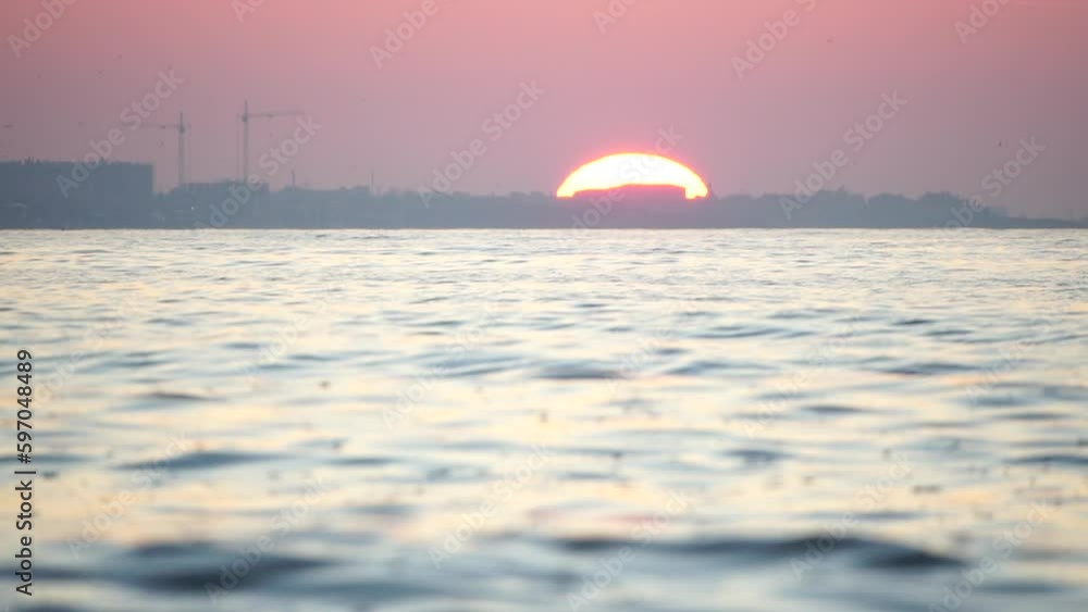 Sunset sea and silhouette of resort town located on the seashore with red sunset sun behind. Holiday recreation concept. Abstract nautical summer ocean sunset nature background. Sunset sea and silhouette of resort town located on the seashore with red sunset sun behind. Holiday recreation concept. Abstract nautical summer ocean sunset nature background.