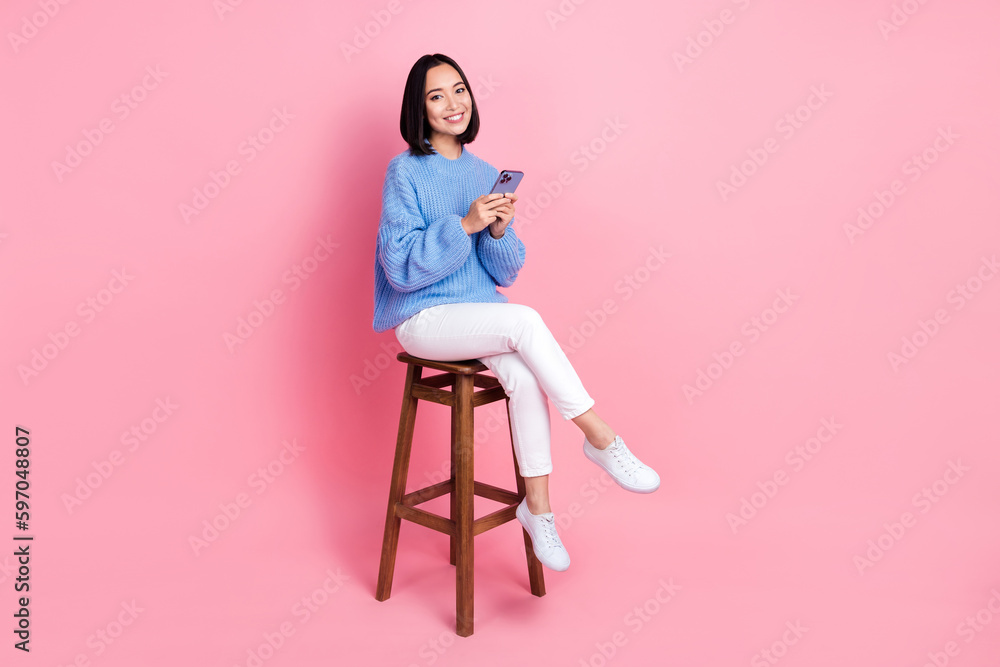 © deagreez - Photo of nice woman wear knit pullover hold smartphone sit on chair facebook twitter instagram whatsapp isolated on pink color background © deagreez - Photo of nice woman wear knit pullover hold smartphone sit on chair facebook twitter instagram whatsapp isolated on pink color background
