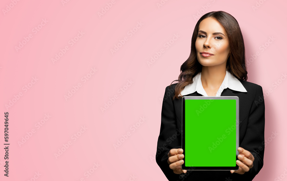 Portrait of young brunette businesswoman showing tablet pc, touchpad, with green chroma key screen, on rose pink background. Confident attractive business woman at office. Portrait of young brunette businesswoman showing tablet pc, touchpad, with green chroma key screen, on rose pink background. Confident attractive business woman at office.