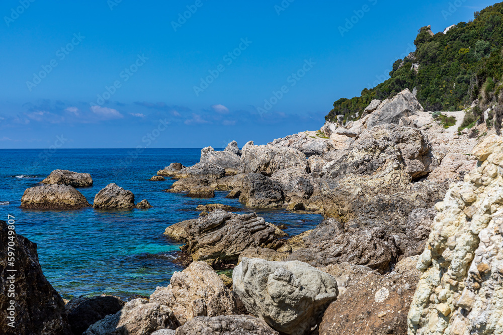 A beautiful landscape of the coast of the island of Corfu in the Ionian Sea of the Mediterranean in Greece. Pure blue clear water washes over the shores of the Greek island. A beautiful landscape of the coast of the island of Corfu in the Ionian Sea of the Mediterranean in Greece. Pure blue clear water washes over the shores of the Greek island.