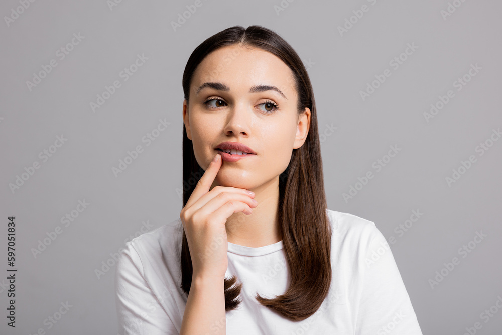 Portrait of beautiful thoughtful woman girl in doubt who stands on grey background wall with copy space shows different emotions isolated. Portrait of beautiful thoughtful woman girl in doubt who stands on grey background wall with copy space shows different emotions isolated.