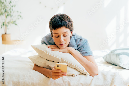 Fototapeta Young attractive woman chatting on the phone while lying lazy on the bed