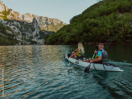 A young couple enjoying an idyllic kayak ride in the middle of a beautiful river surrounded by forest greenery