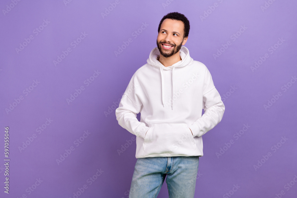 Photo of cheerful friendly man with curly hairstyle dressed white hoodie look at sale empty space isolated on purple color background Photo of cheerful friendly man with curly hairstyle dressed white hoodie look at sale empty space isolated on purple color background